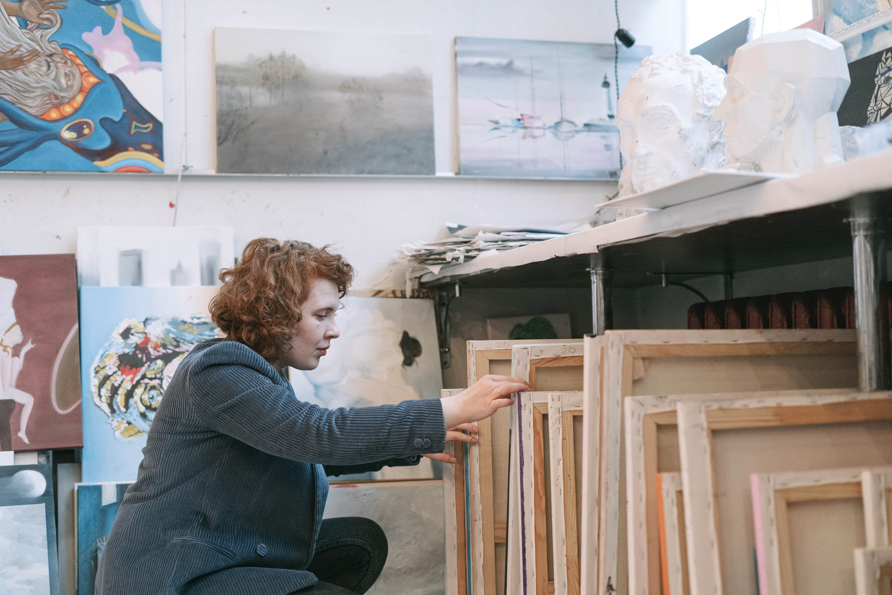 A Woman Looking Through the Canvases Under the Table